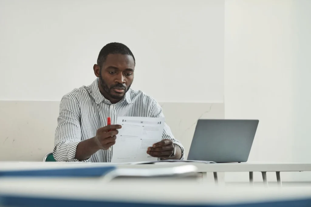Candidate preparing for IT certification exams with study notes and a laptop