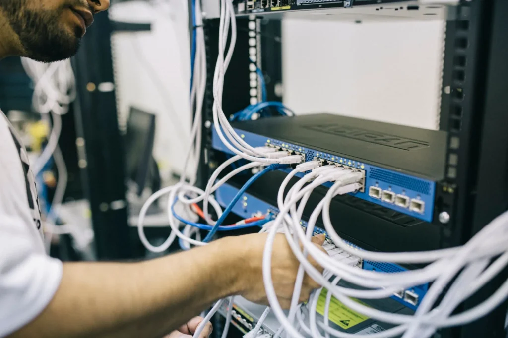 Network technician organizing ethernet cables in a server rack with labeled switch ports
