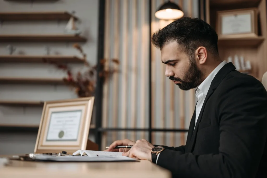 IT professional reviewing certification study materials at a desk with laptop and notes